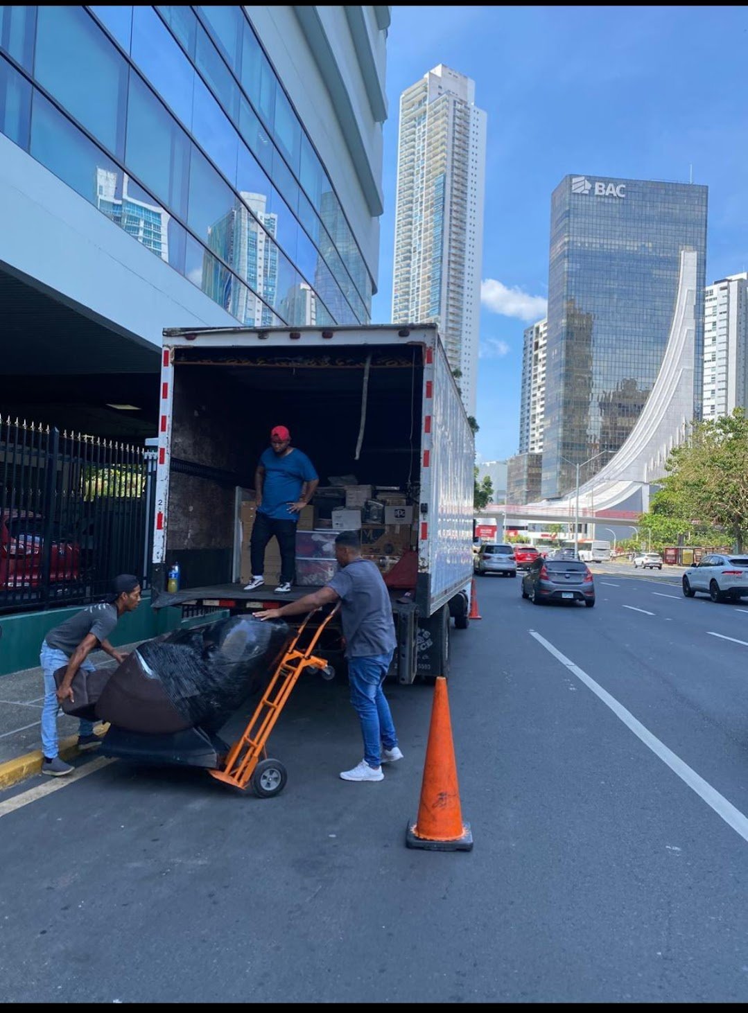 Camión de mudanza siendo descargado en ciudad con trabajadores搬运行李